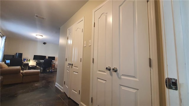 corridor featuring an office area, concrete flooring, and baseboards
