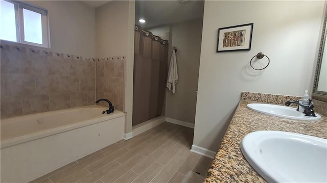 full bathroom featuring a shower stall, a bath, baseboards, and double vanity