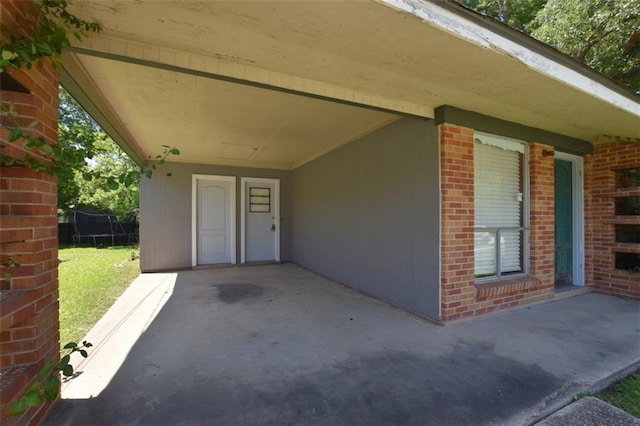 doorway to property featuring a patio and brick siding