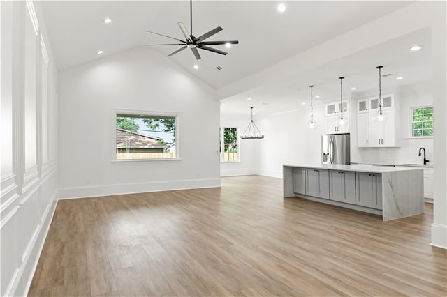 unfurnished living room with light wood finished floors, a healthy amount of sunlight, recessed lighting, and ceiling fan with notable chandelier