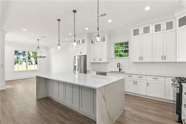 kitchen featuring a sink, white cabinetry, a kitchen island, and appliances with stainless steel finishes