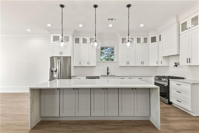 kitchen featuring a spacious island, visible vents, a sink, backsplash, and stainless steel appliances