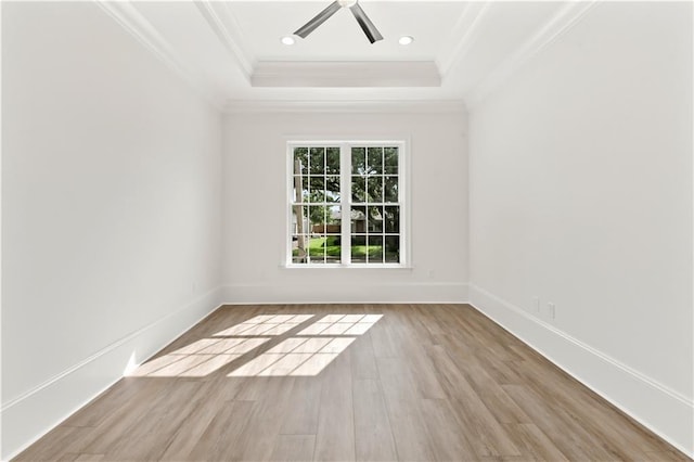 unfurnished room with wood finished floors, crown molding, a ceiling fan, a raised ceiling, and baseboards