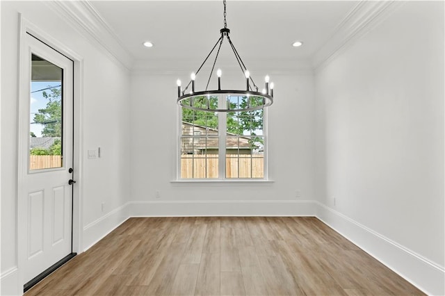 unfurnished dining area featuring an inviting chandelier, light wood-type flooring, baseboards, and crown molding