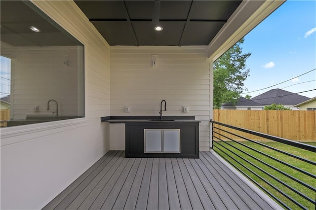 wooden terrace featuring a yard, a sink, and fence