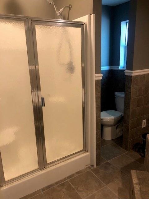 362 W Ave, Harahan, LA 70123 - bathroom featuring tile walls, toilet, a wainscoted wall, tile patterned floors, and a stall shower