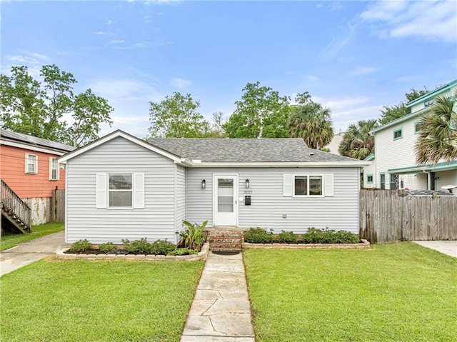 ranch-style house with fence, a shingled roof, and a front yard