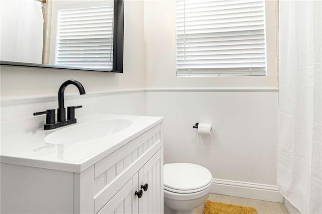 full bath featuring vanity, curtained shower, toilet, and wainscoting