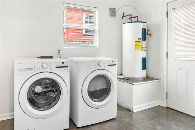 washroom with baseboards, washer and dryer, dark tile patterned flooring, electric water heater, and laundry area