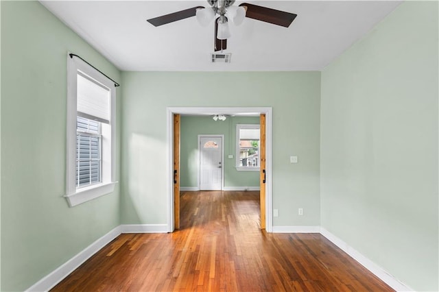 unfurnished room with baseboards, ceiling fan, visible vents, and wood finished floors