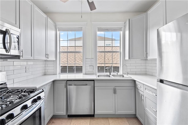 kitchen with light countertops, stainless steel appliances, a ceiling fan, and a sink
