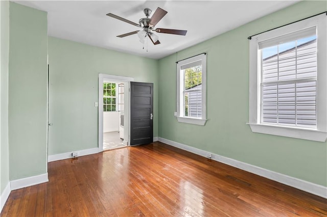 unfurnished bedroom with ceiling fan, hardwood / wood-style flooring, baseboards, and multiple windows