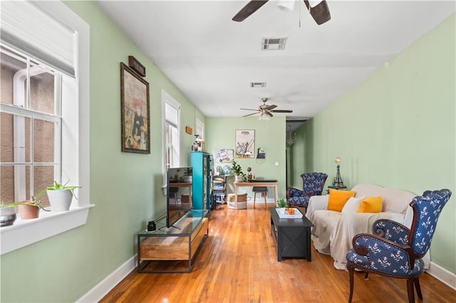 living area featuring a ceiling fan, wood finished floors, and baseboards