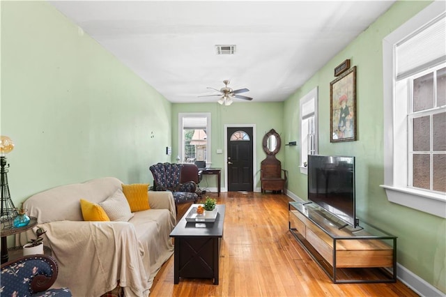 living area with baseboards, visible vents, light wood-style flooring, and a ceiling fan