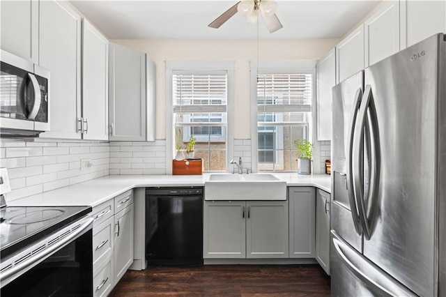 kitchen featuring ceiling fan, a sink, gray cabinets, appliances with stainless steel finishes, and dark wood-style floors