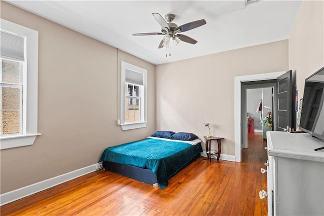 bedroom with ceiling fan, wood-type flooring, and baseboards