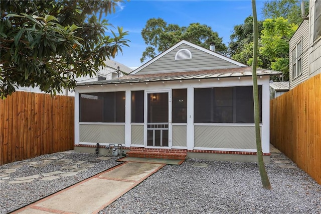 back of property with a sunroom, roof with shingles, entry steps, and a fenced backyard
