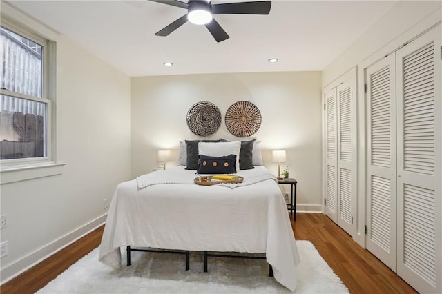 bedroom with baseboards, multiple closets, ceiling fan, and wood finished floors