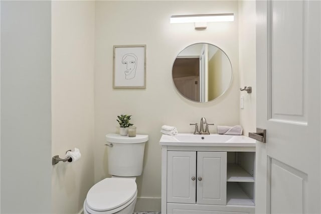half bath with vanity, toilet, and baseboards