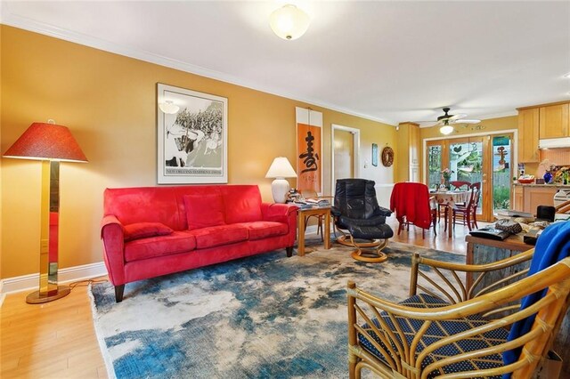 living area featuring crown molding, a ceiling fan, wood finished floors, and baseboards