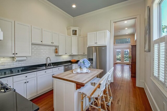 kitchen featuring a sink, appliances with stainless steel finishes, wooden counters, white cabinets, and tasteful backsplash