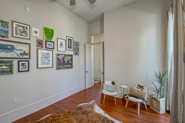 living area featuring wood finished floors, ceiling fan, and baseboards