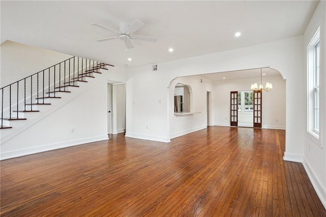 unfurnished living room featuring hardwood / wood-style floors, ceiling fan, a chandelier, arched walkways, and recessed lighting