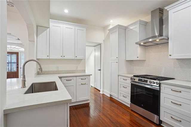 kitchen featuring stainless steel range with gas cooktop, wall chimney exhaust hood, a sink, dark wood finished floors, and decorative backsplash