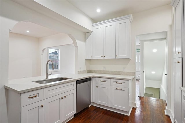 kitchen featuring stainless steel dishwasher, a sink, white cabinets, arched walkways, and recessed lighting
