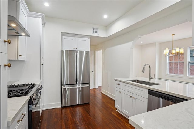 kitchen with appliances with stainless steel finishes, a sink, dark wood-style flooring, under cabinet range hood, and a chandelier