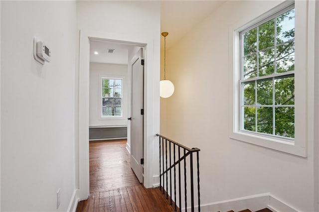 hallway with dark wood finished floors, an upstairs landing, and baseboards