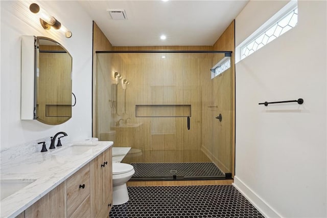 full bathroom featuring toilet, a shower stall, and double vanity