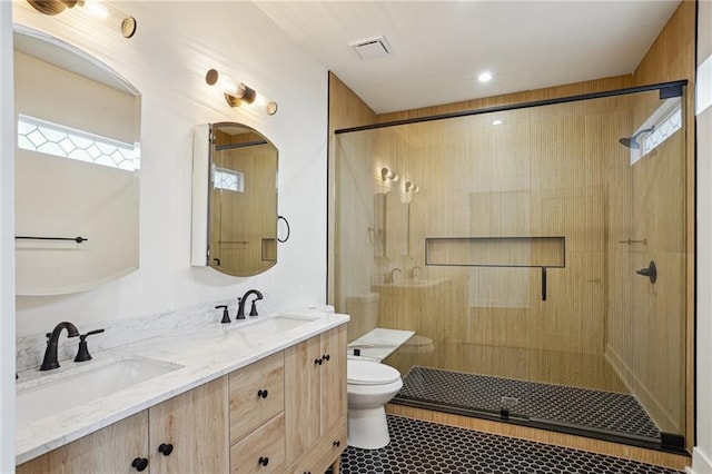bathroom featuring toilet, a stall shower, and double vanity