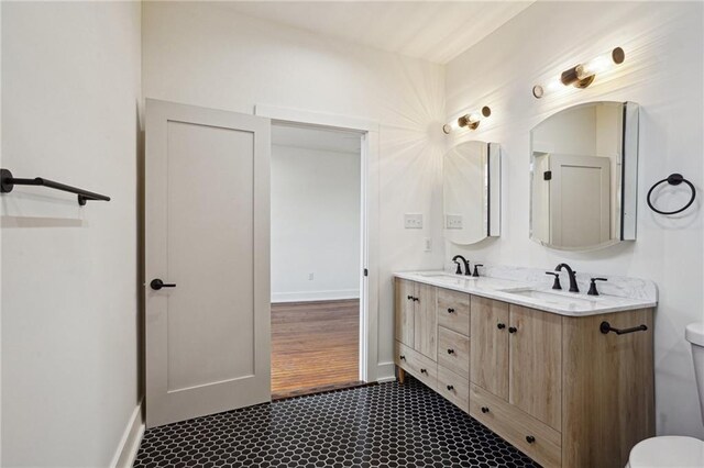full bathroom featuring toilet, double vanity, and baseboards