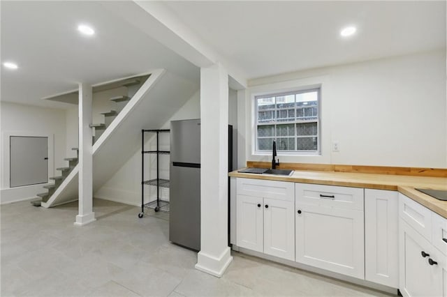 bar area featuring a sink, freestanding refrigerator, stairway, recessed lighting, and baseboards