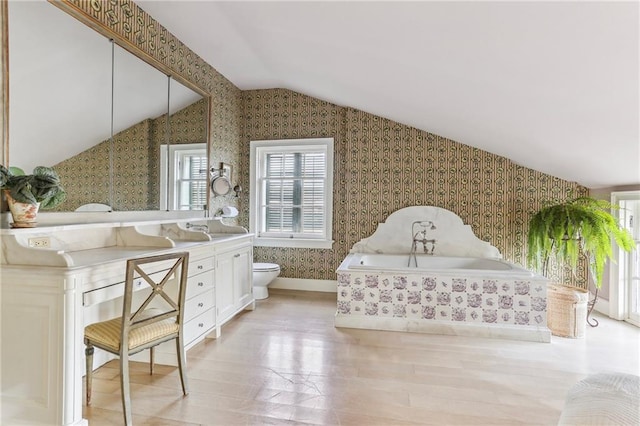 600 Governor Nicholls St, New Orleans, LA 70116 - bathroom with wallpapered walls, vaulted ceiling, a bath, toilet, and wood finished floors