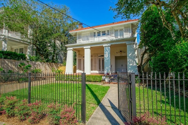 view of front of home with a porch, a fenced front yard, a front lawn, and a balcony