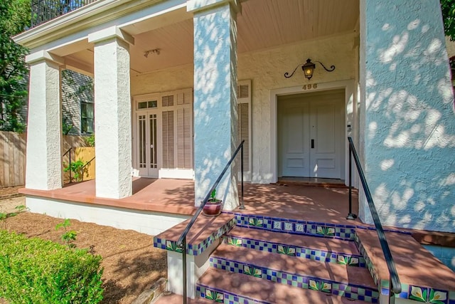 doorway to property featuring a porch and stucco siding