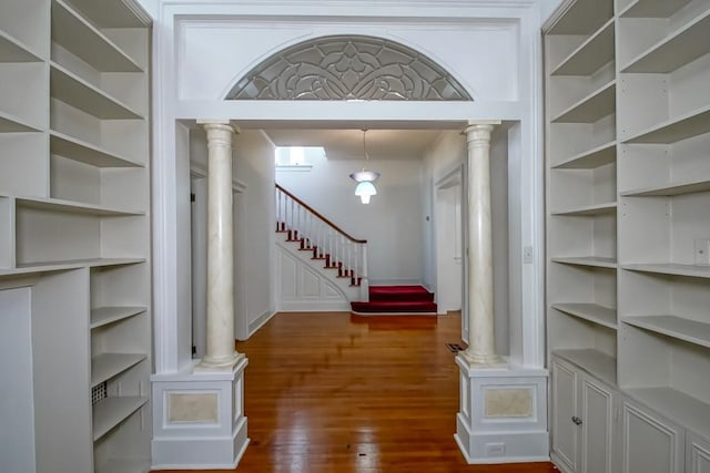 interior space with dark wood finished floors, stairway, and ornate columns