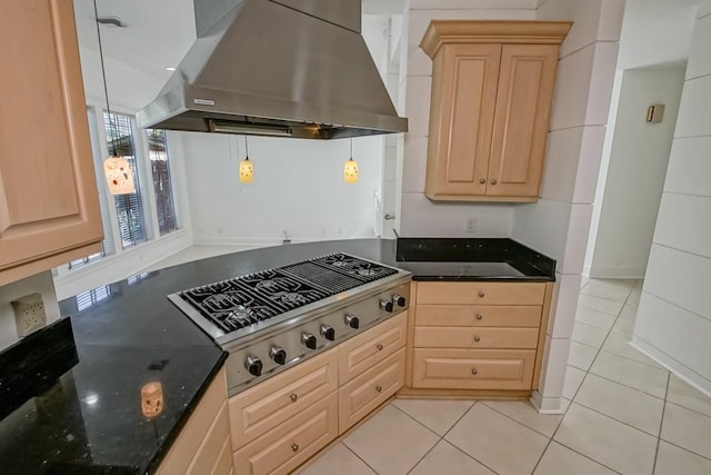 kitchen with light brown cabinetry, stainless steel gas cooktop, light tile patterned flooring, dark stone countertops, and island range hood