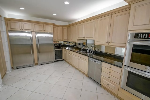 kitchen featuring light brown cabinets, recessed lighting, beverage cooler, a sink, and stainless steel appliances