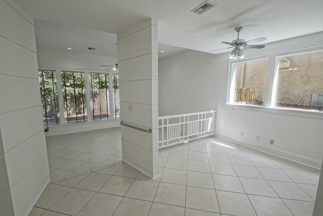 empty room featuring light tile patterned floors, baseboards, visible vents, and ceiling fan