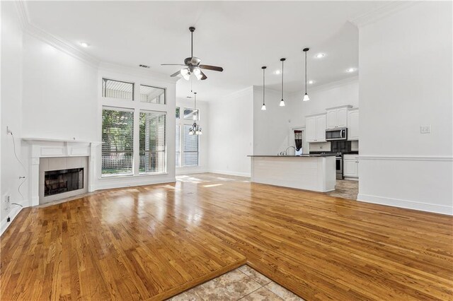 400 Brown Thrasher Loop, Madisonville, LA 70447 - unfurnished living room with ceiling fan, a tile fireplace, baseboards, light wood-style floors, and ornamental molding
