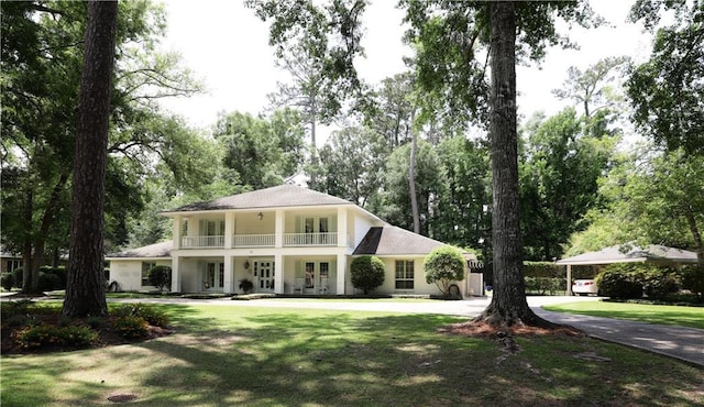 greek revival inspired property featuring a balcony, a front yard, french doors, and curved driveway