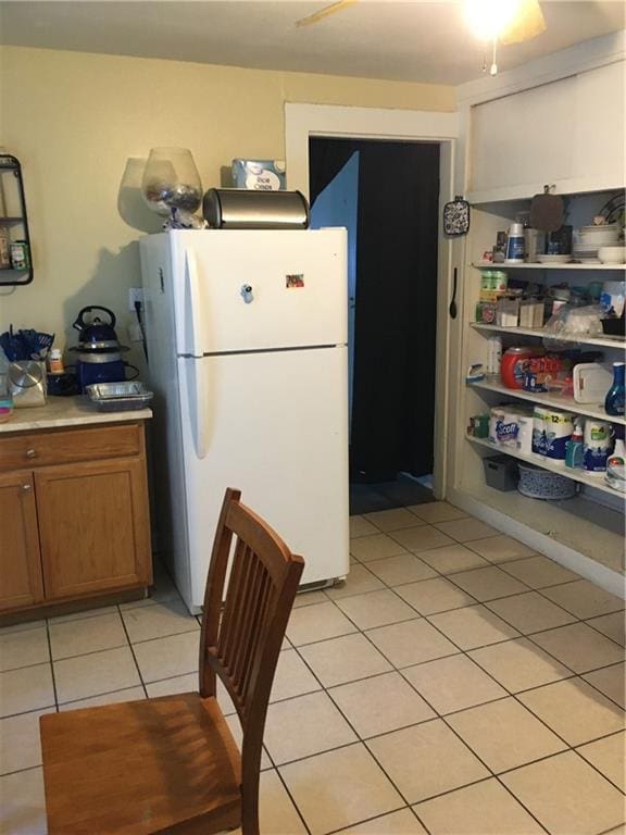 201315 Touro St, New Orleans, LA 70116 - kitchen with freestanding refrigerator, brown cabinets, light tile patterned flooring, and light countertops
