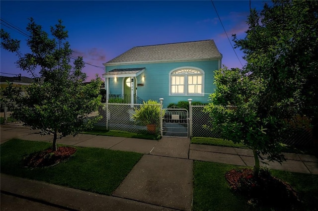 view of front of property with a fenced front yard, a gate, and a shingled roof