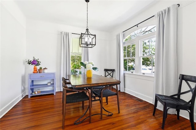 dining space featuring a chandelier, dark wood finished floors, and baseboards