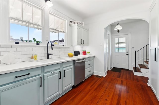 kitchen featuring a sink, arched walkways, dishwasher, and backsplash