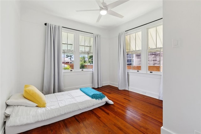 bedroom featuring wood finished floors, baseboards, and ceiling fan