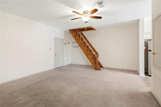 unfurnished living room with a ceiling fan, light colored carpet, stairs, and baseboards